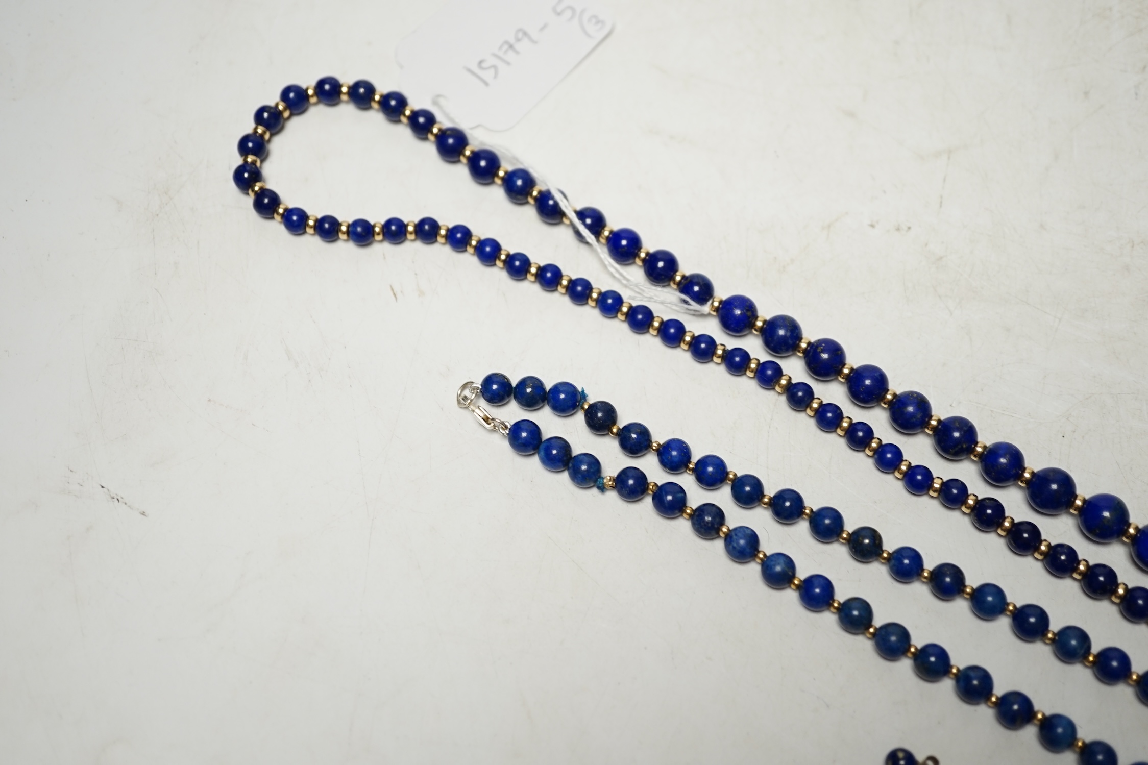 Two lapis lazuli bead necklaces with yellow metal spacers, largest 76cm and a pair of earrings. Condition - fair